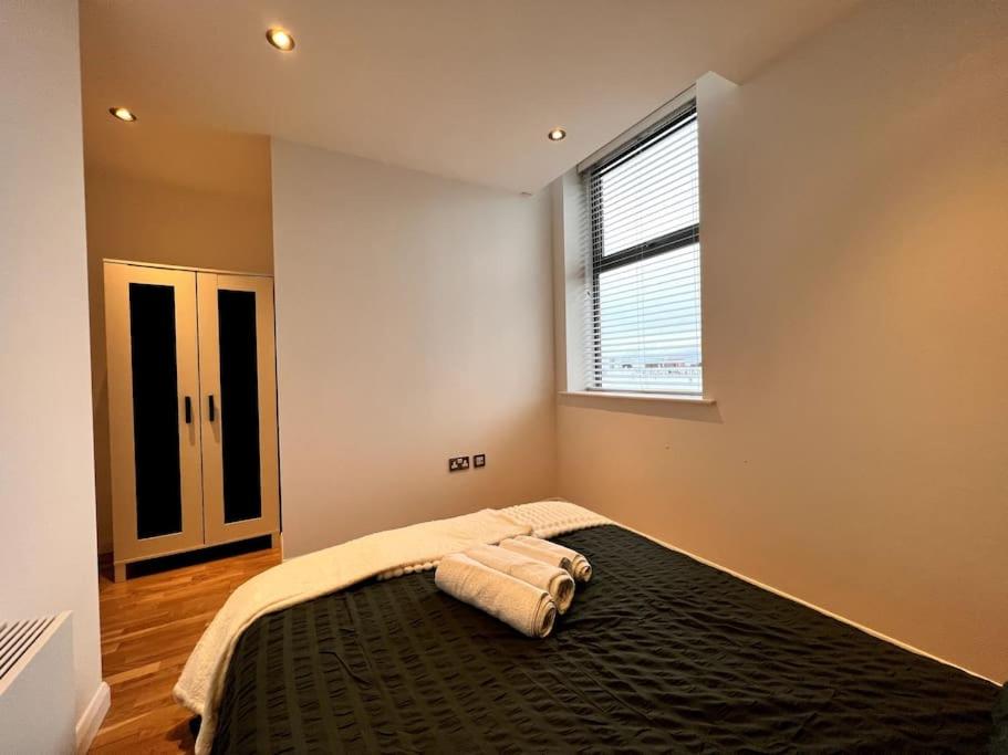 ein Schlafzimmer mit einem Bett mit einer schwarzen Decke und einem Fenster in der Unterkunft Beautiful 1 Bed Flat close to Clapham Trendy in London