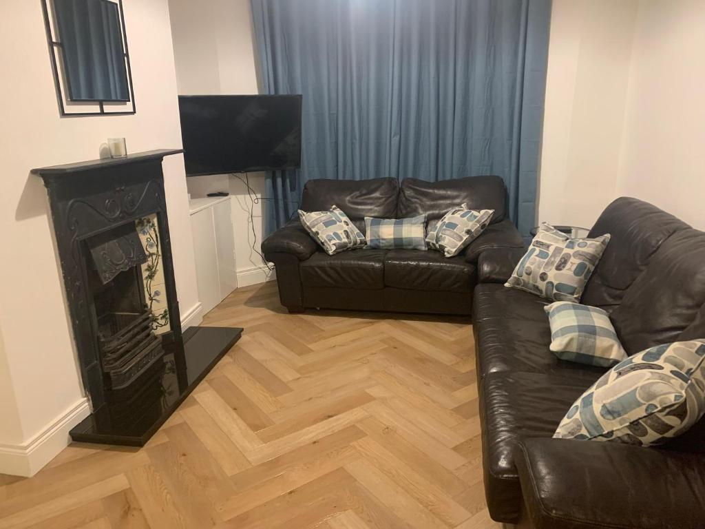 a living room with a leather couch and a fireplace at Prospect House in Bangor