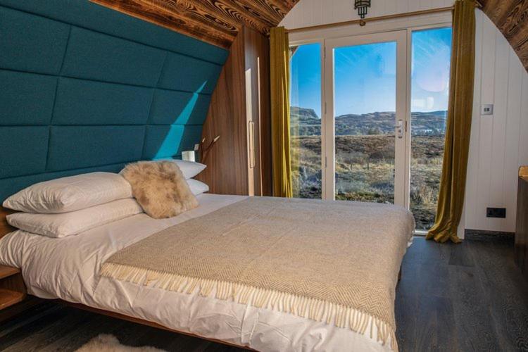 a bedroom with a large bed with a large window at Bracken Hide Hotel in Portree
