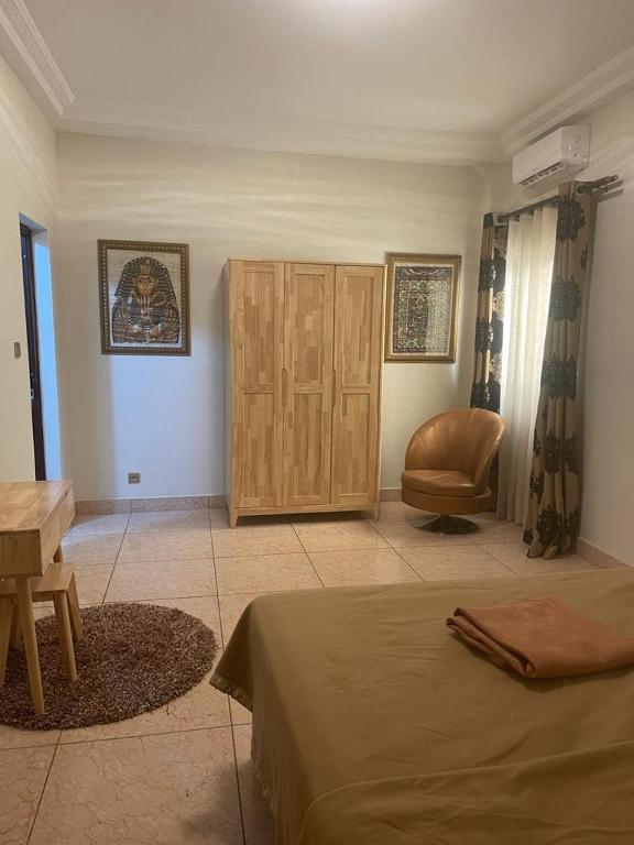 a room with two beds and a chair in it at Studio meuble sacre cœur in Dakar