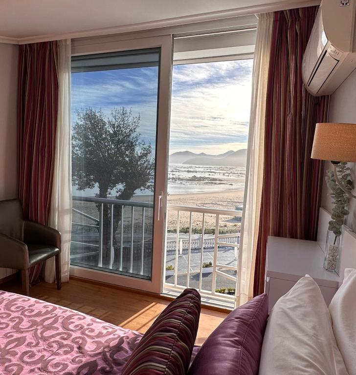 a hotel room with a bed and a large window at Hotel Las Olas in Noja