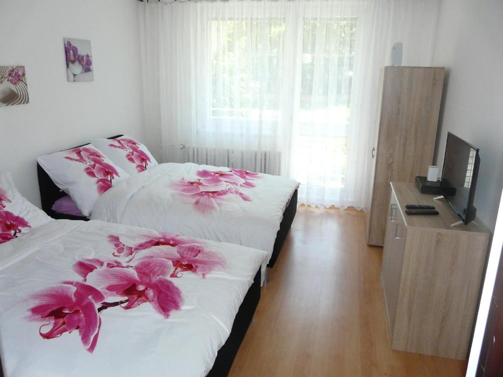 - une chambre avec 2 lits avec des fleurs roses dans l'établissement Apartment Fialka, à Olomouc
