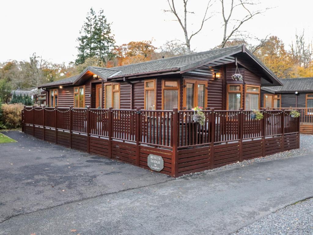 a wooden cabin with a fence in front of it at Ruskin Lodge in Windermere