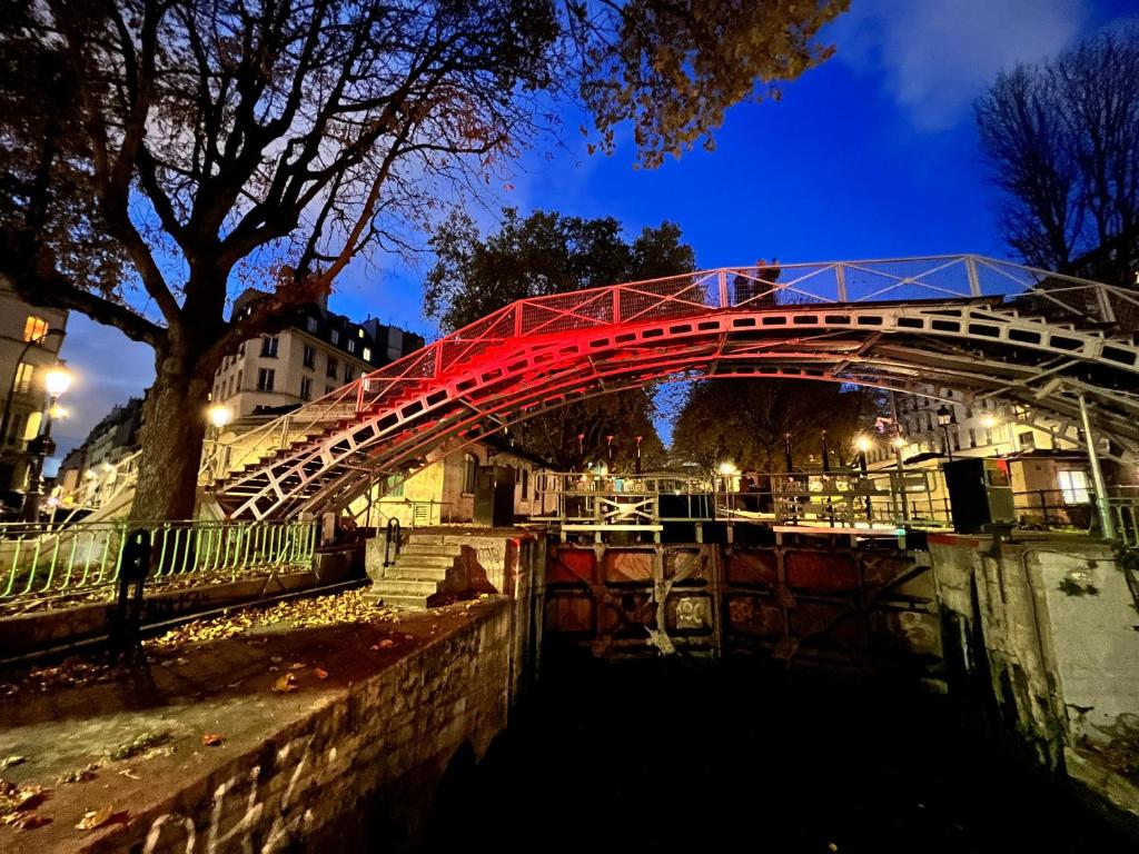 a red bridge over a river at night at Rooms with fabulous view on Paris roofs in Paris