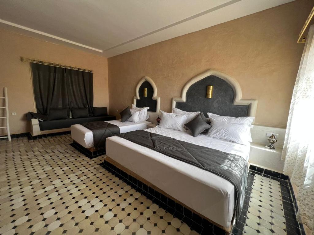 a hotel room with two beds and a chair at Riad Akabar Merzouga in Merzouga
