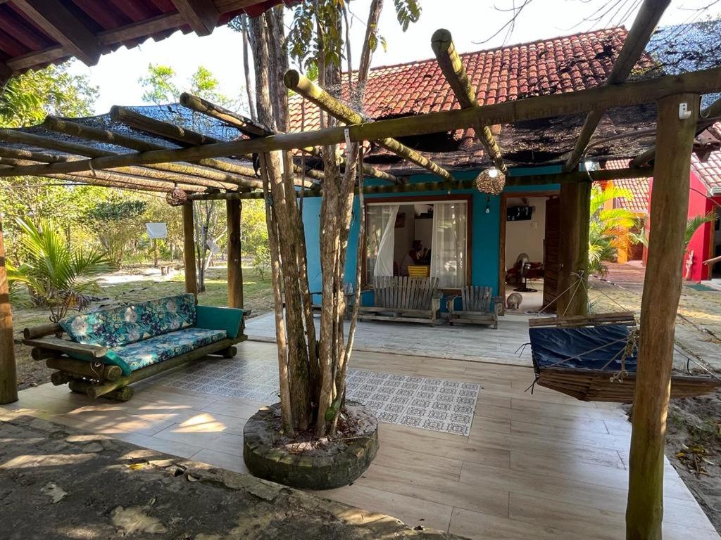 eine überdachte Terrasse mit einem Sofa und einem Baum in der Unterkunft Chalé Paraíso Corumbau - Chalés Uvas Azul in Corumbau