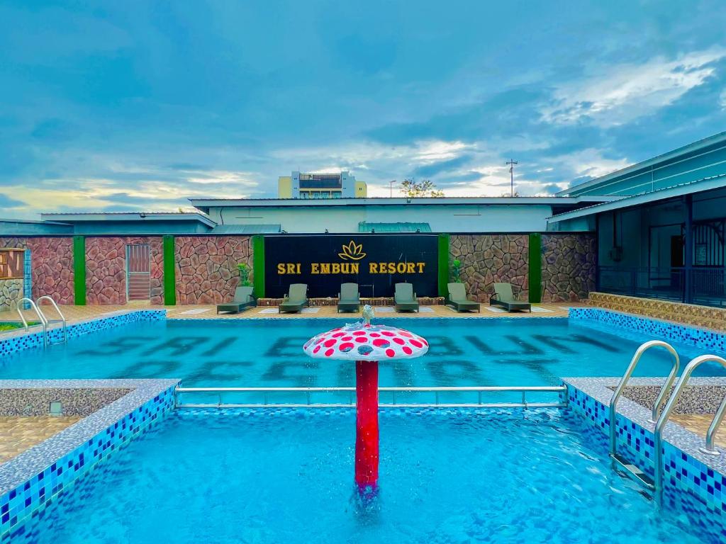 una piscina con sombrilla frente a un hotel en Sri Embun Resort Langkawi en Pantai Cenang