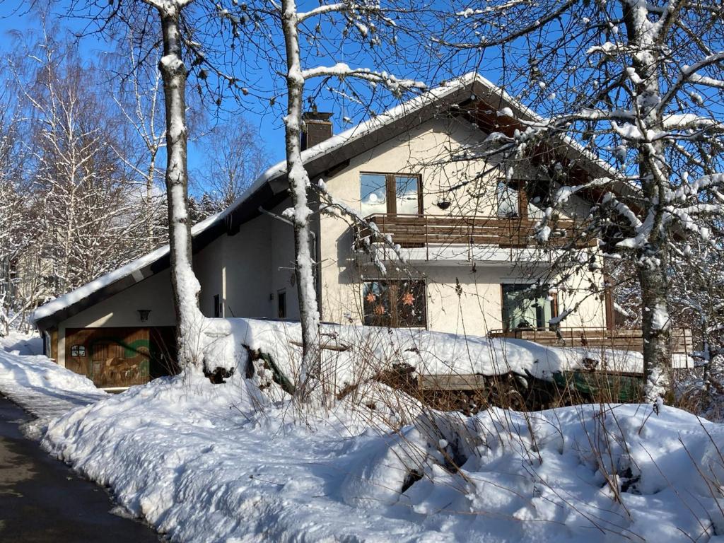 Ferienwohnung Tannenblick - 3 Schlafzimmer, Feldberg-Falkau في Hinterfalkau: منزل مغطى بالثلج في الغابة