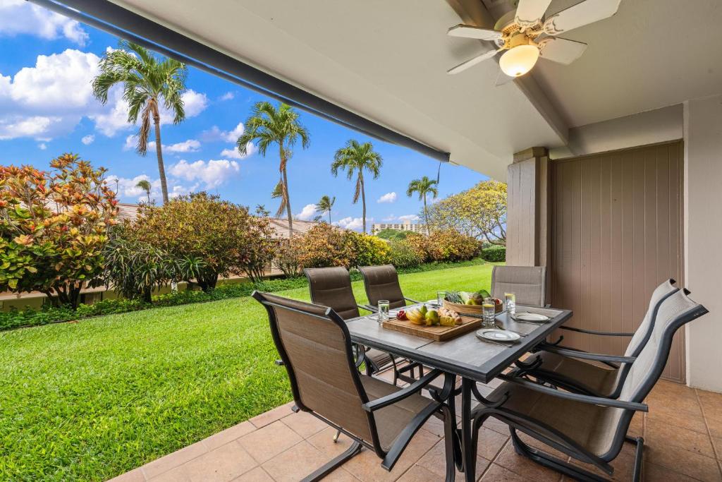 a patio with a table and chairs and a lawn at Eldorado L102 in Kahana