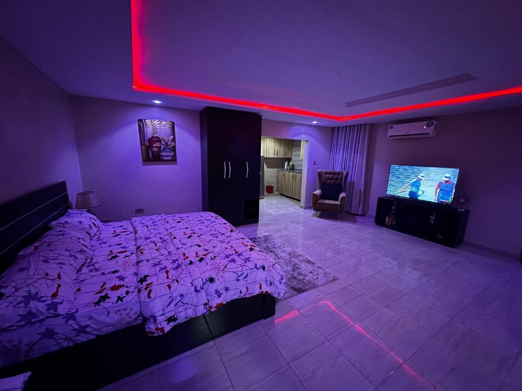 ein lila Schlafzimmer mit einem Bett und einem Flachbild-TV in der Unterkunft Osmosis Ikoyi in Lagos