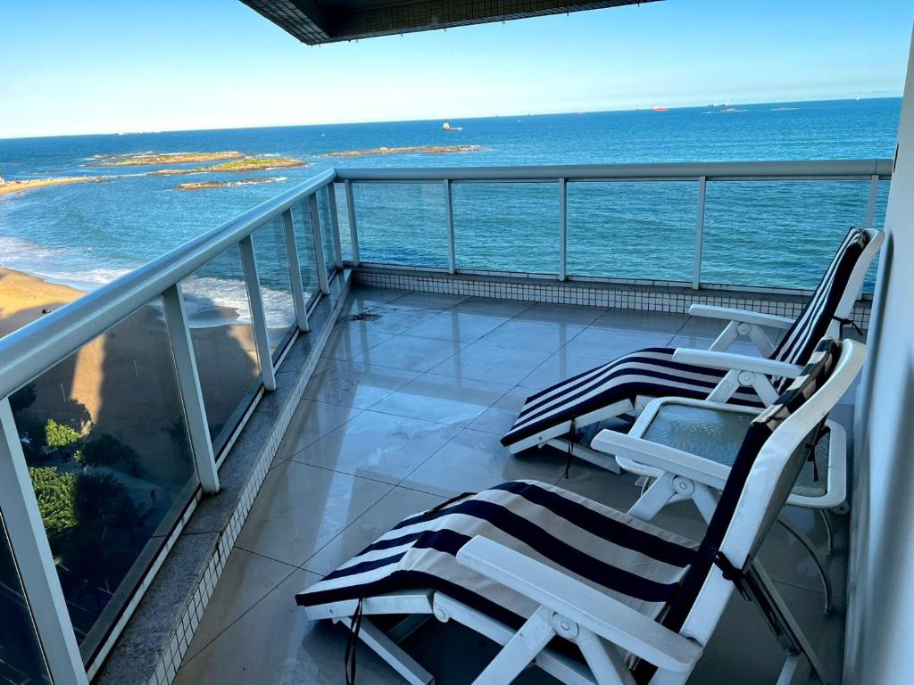 two lounge chairs on a balcony overlooking the ocean at Apartamento Frente Mar in Vila Velha