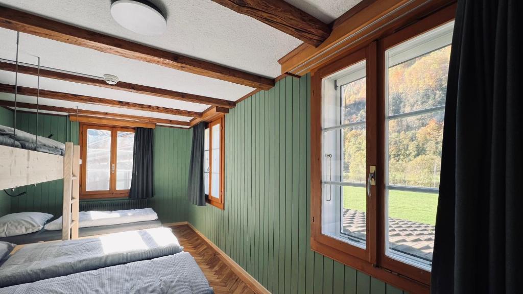 a bedroom with green walls and a large window at Alpina Einhorn - Self-Check-In in Wolfenschiessen
