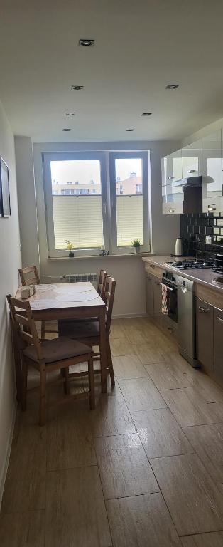 a kitchen with a table and chairs and windows at Apartament Busko-Zdrój - Zosia in Busko-Zdrój