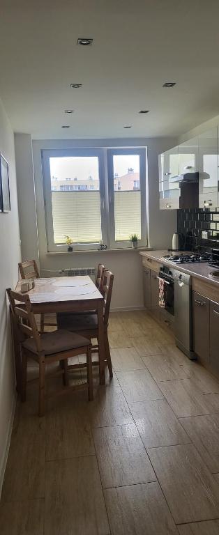 kuchnia ze stołem, krzesłami i oknami w obiekcie Apartament Busko-Zdrój - Zosia w Busku Zdroju