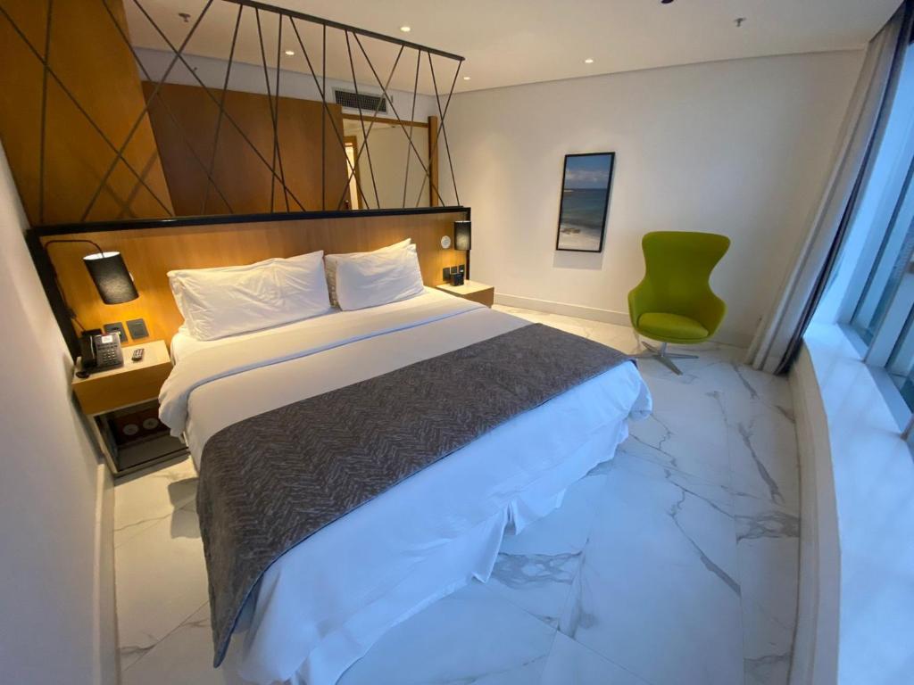 a bedroom with a large bed and a green chair at Hotel Nacional Rio de Janeiro in Rio de Janeiro