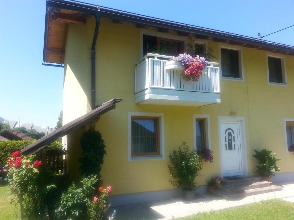 una casa amarilla con un balcón con flores. en Apartment Katzer, en Tröpolach