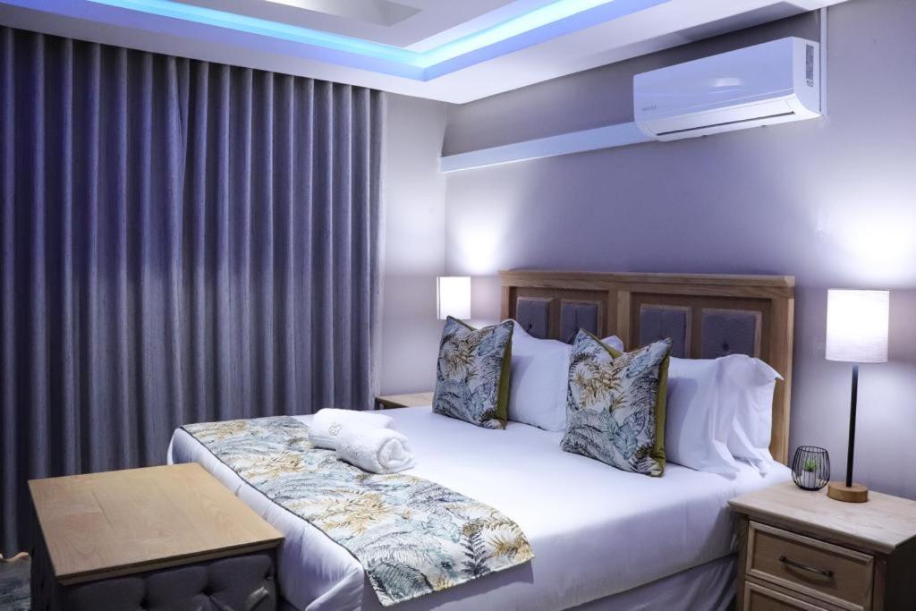 EDEN BOUTIQUE HOTEL في كوكستاد: غرفة نوم بسرير كبير عليها شراشف ووسائد بيضاء
