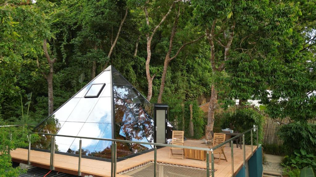 a tent with a deck and chairs in front of trees at Unique Stays at Karuna El Nido - The Pyramid in El Nido