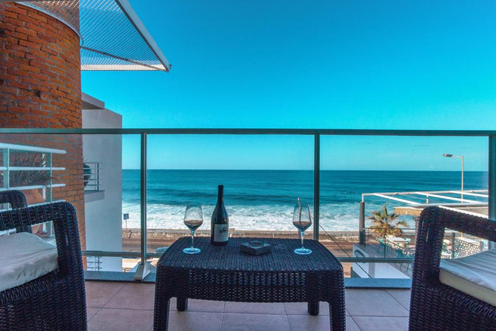 a table with wine glasses on a balcony with the ocean at Apartment 7 on Paul do Mar Beach in Paul do Mar