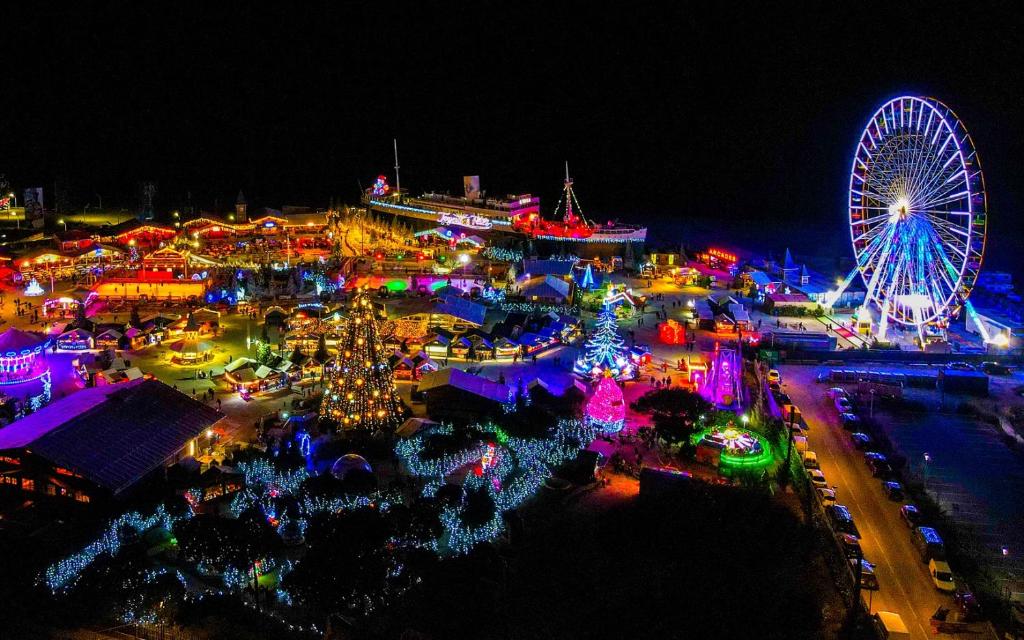 uma vista aérea de um carnaval à noite com uma roda gigante em Mas bleu île des pêcheurs em Le Barcarès