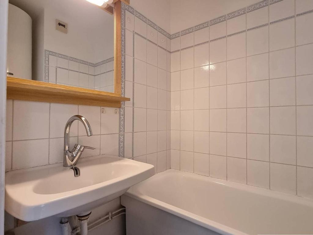 La salle de bains blanche est pourvue d'un lavabo et d'une baignoire. dans l'établissement Appartement 2 pièces, 5 pers, proche pistes, commerces et télésiège, parking gratuit - FR-1-525-267, à Saint-Étienne-en-Dévoluy
