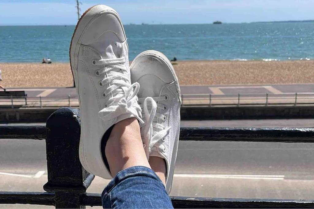 a person sitting on a rail with their shoes on the beach at Luxury on the beach in Portsmouth