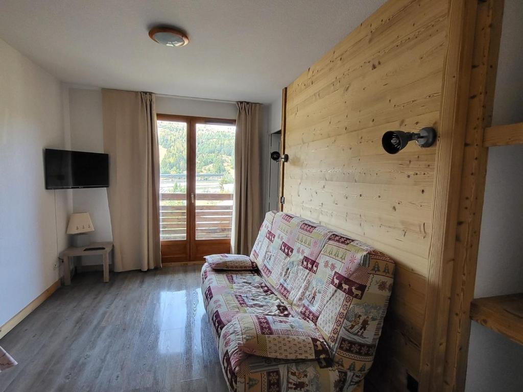 a living room with a couch and a wooden wall at Appartement Le Dévoluy, 2 pièces, 4 personnes - FR-1-504-672 in Le Dévoluy