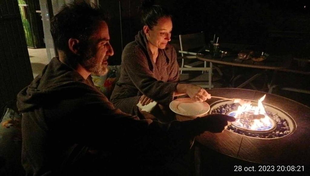 un hombre y una mujer sentados en una mesa con fuego en SIANDAKI NID D AMOUR AVEC JACUZZI, en La Motte