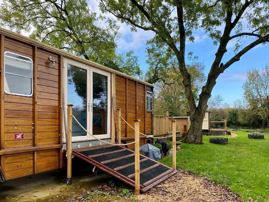 a wooden tiny house with a porch and a tree at Bessie - Uk45591 in Seend