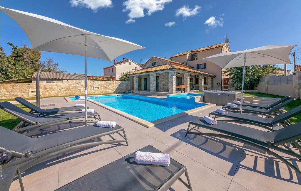 - une piscine avec des chaises et des parasols en face d'une maison dans l'établissement Villa M, à Poreč