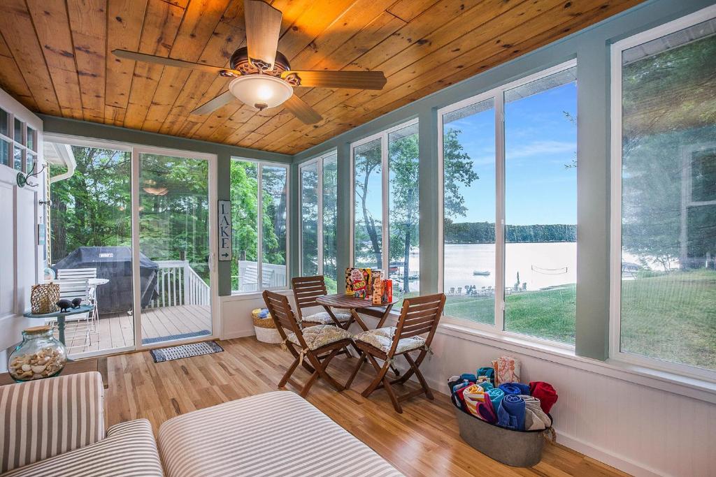 a living room with a table and chairs and windows at Waterfront Newaygo Cottage with Private Dock and Beach in Newaygo