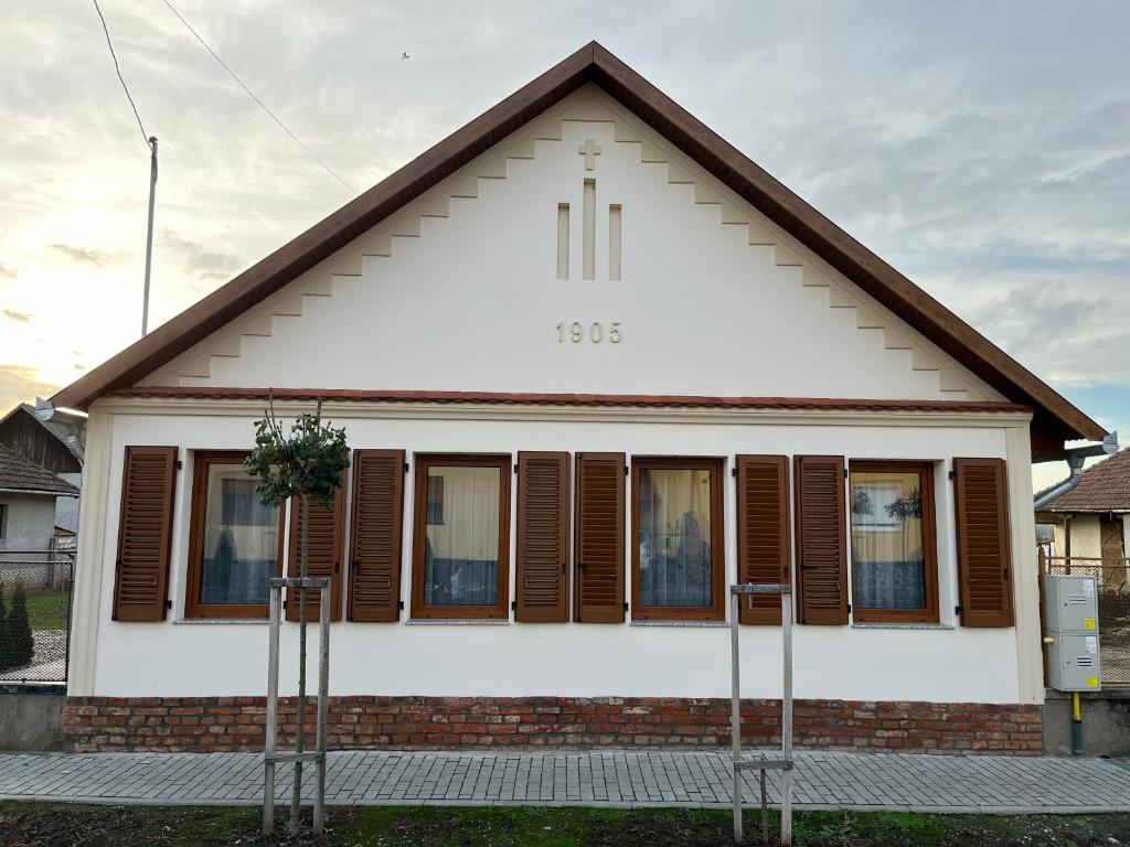 Casa blanca con ventanas con persianas marrones en Engstliz House, en Foeni