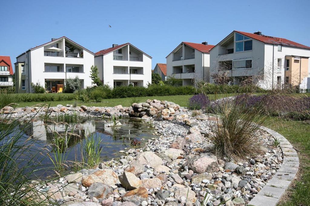 einen Teich in einem Hof mit Häusern und Eigentumswohnungen in der Unterkunft Apartments Büsumer Ring in Kühlungsborn