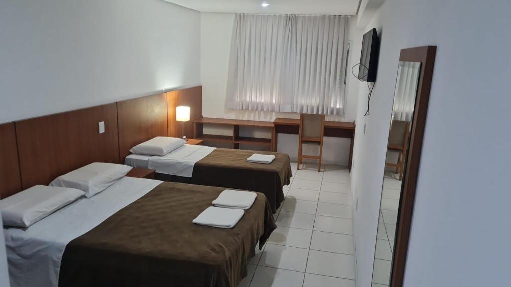 um quarto de hotel com duas camas e uma televisão em HOTEL ECONOMICO - 150m Santa Casa, Prox Assembleia e UFRGS em Porto Alegre