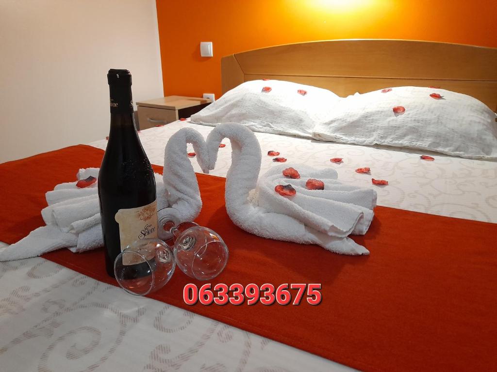 dwa łabędzie z kieliszkami do wina i butelką na łóżku w obiekcie Sobe i apartmani Kety w mieście Kragujevac