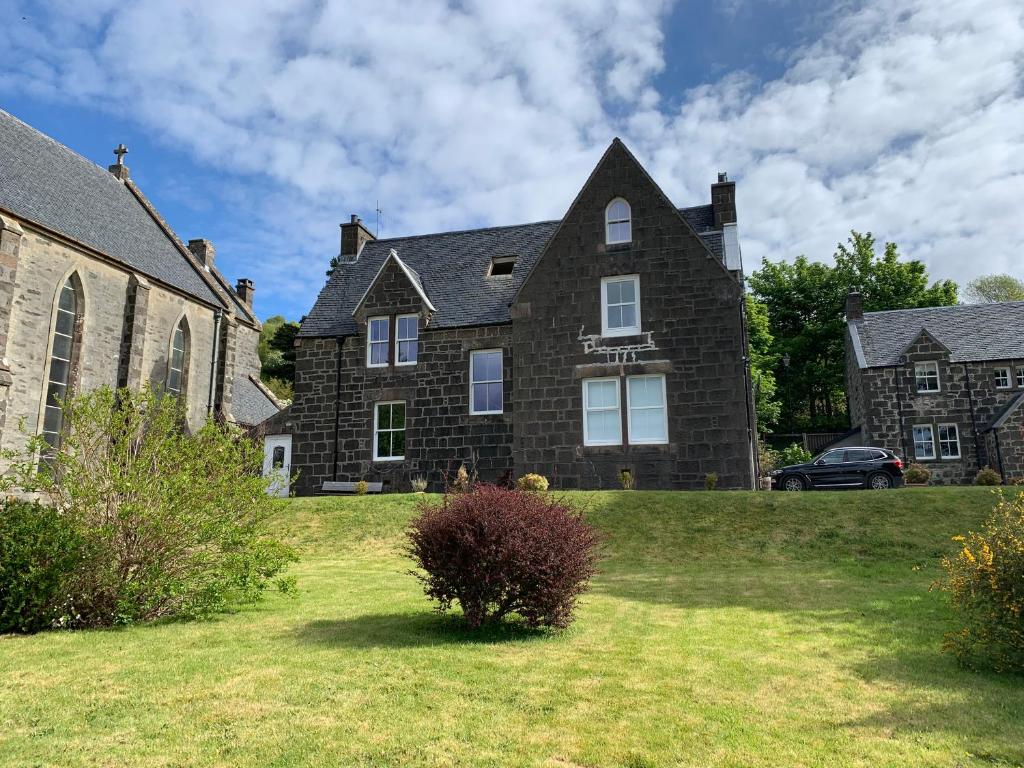 a large brick house on a grassy yard at Victorian Chapel House in Arisaig