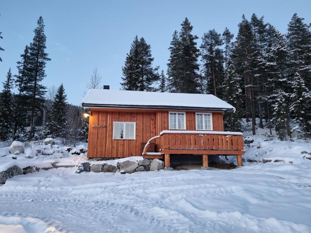 a wooden cabin with a bench in the snow at Nytt anneks med fantastisk utsikt over Hallingdal. in Gol