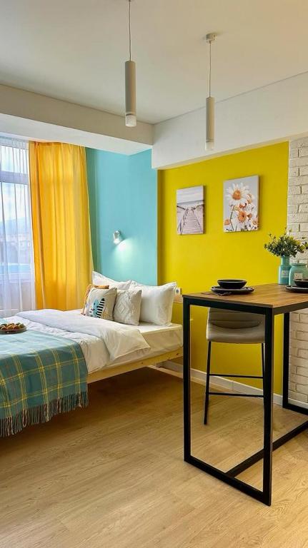 a bedroom with a bed and a table and yellow walls at Апартаменты в ЖК ТаунХаус in Kokshetau