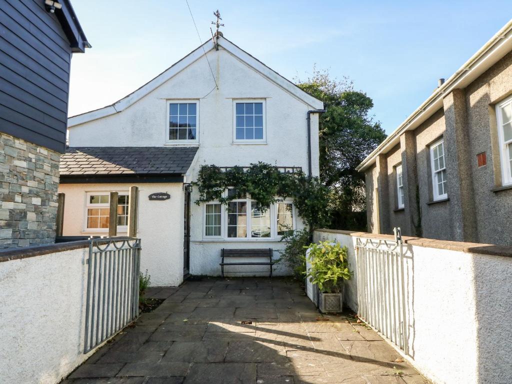 una casa bianca con una panchina davanti di The Cottage a Pwllheli