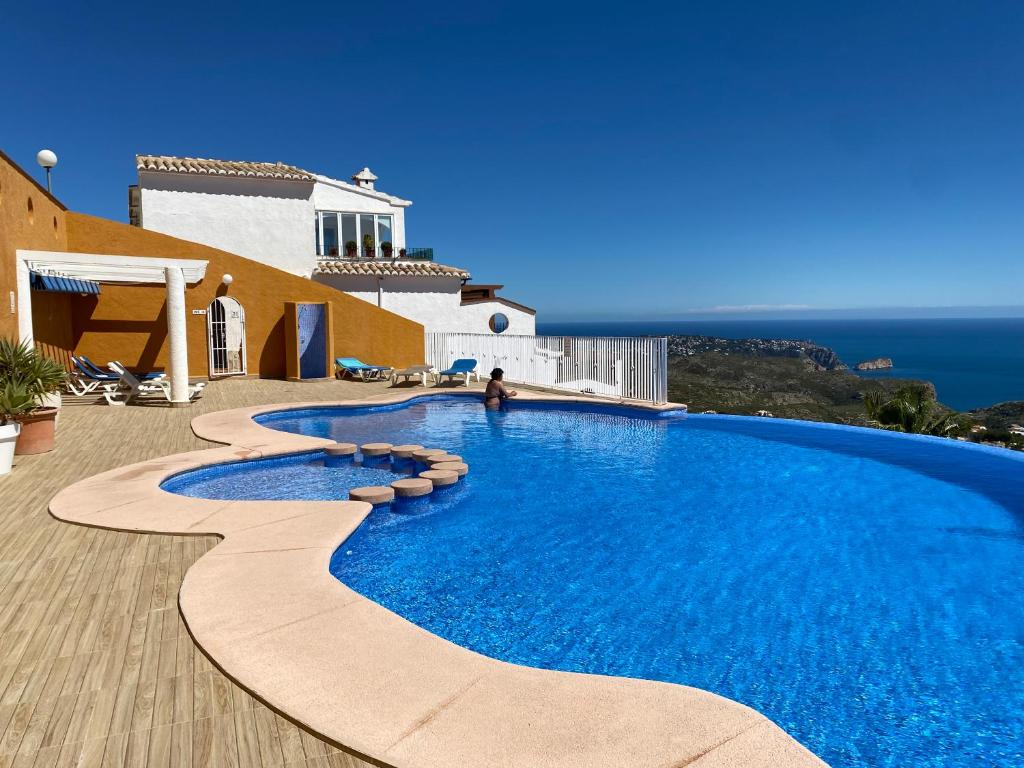 a swimming pool on the side of a house with the ocean at Amazing vue mer CASAZAZA in Benitachell