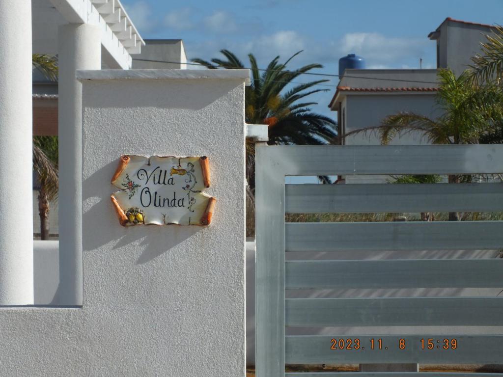 Una recinzione bianca con un cartello che dice tutto unito di Villa Olinda a Triscina
