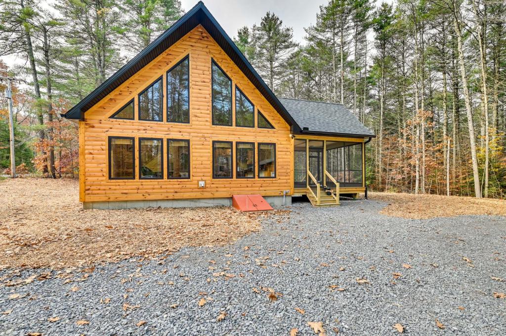a log cabin in the woods with a lot of windows at Modern Cabin with Hot Tub and Sacandaga Lake Access! in Broadalbin
