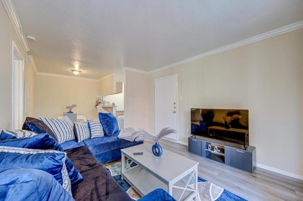 a living room with a blue couch and a tv at Elegant Houston Hub MedCtr,NRG,Galleria,Museum District in Houston