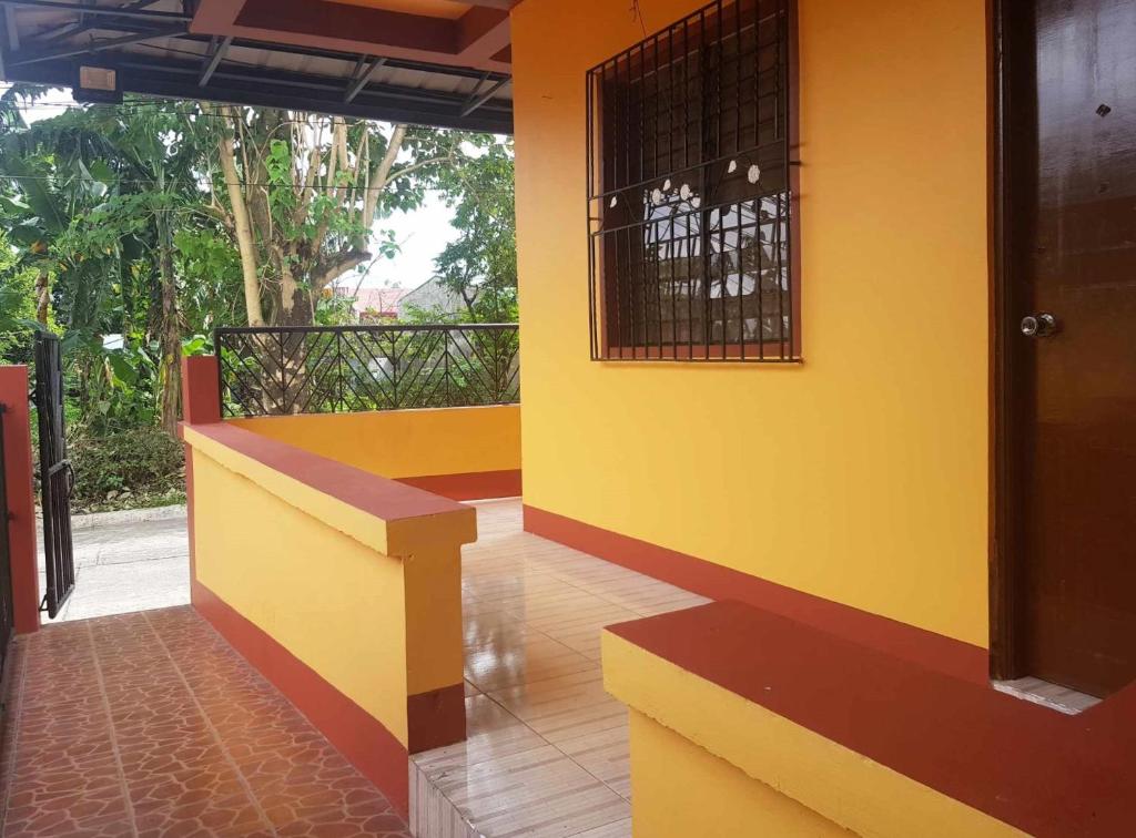 a yellow wall with a bench on a balcony at RM3 - Ground Floor Unit in San Roque Bauan Batangas in Batangas City