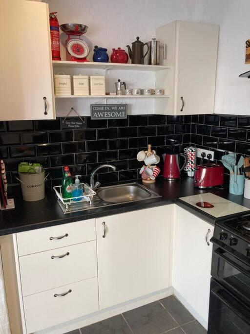 a kitchen with white cabinets and a sink at The Potters Cottage in Clifden