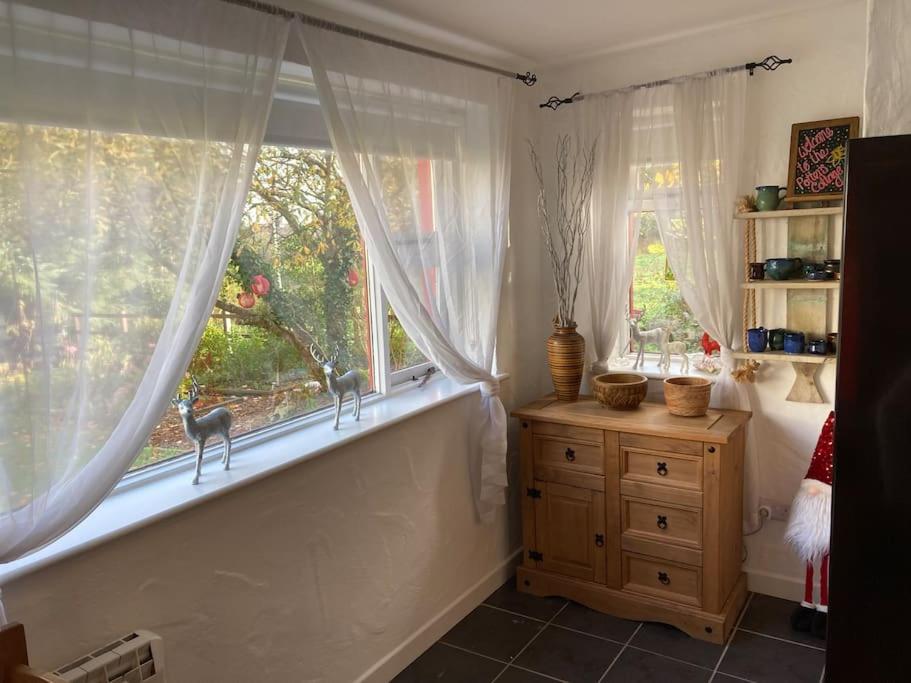 a room with two windows and a wooden dresser in front at The Potters Cottage in Clifden