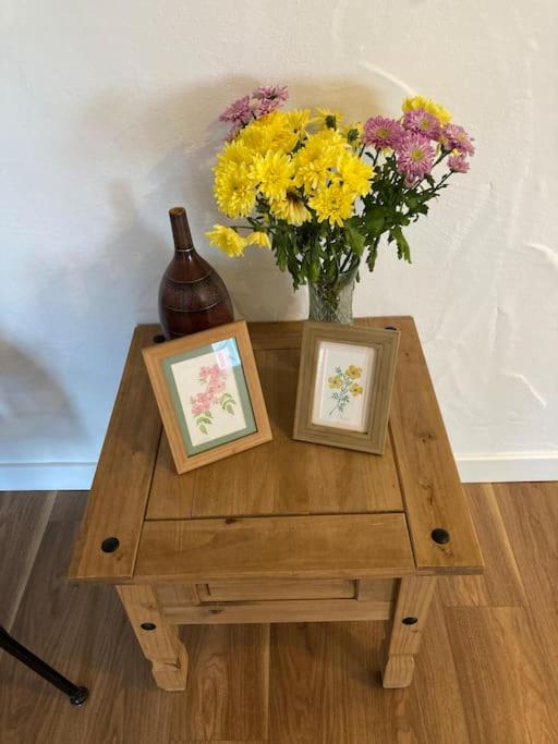 a table with two pictures and a vase of flowers at The Potters Cottage in Clifden