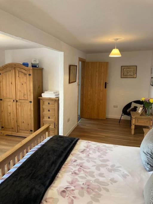 a bedroom with a large bed with a dresser and a desk at The Potters Cottage in Clifden