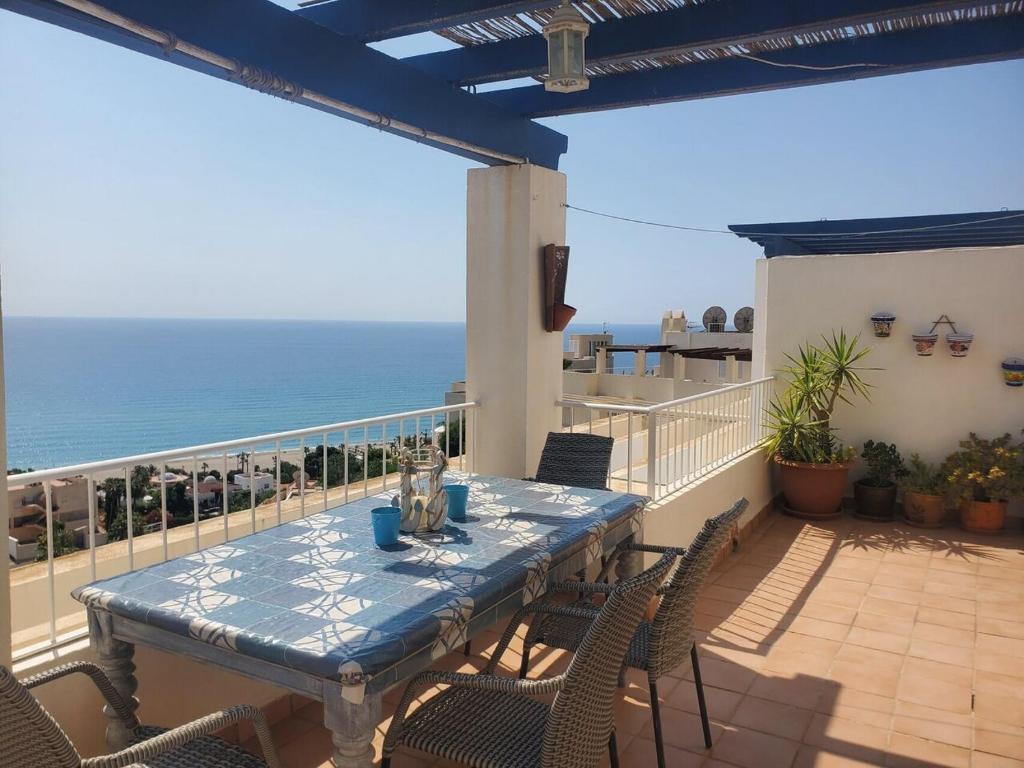 Mojacar Bella - Penthouse - Sleeps 4 - R065 في موجاكار: طاولة زرقاء وكراسي على شرفة مع المحيط