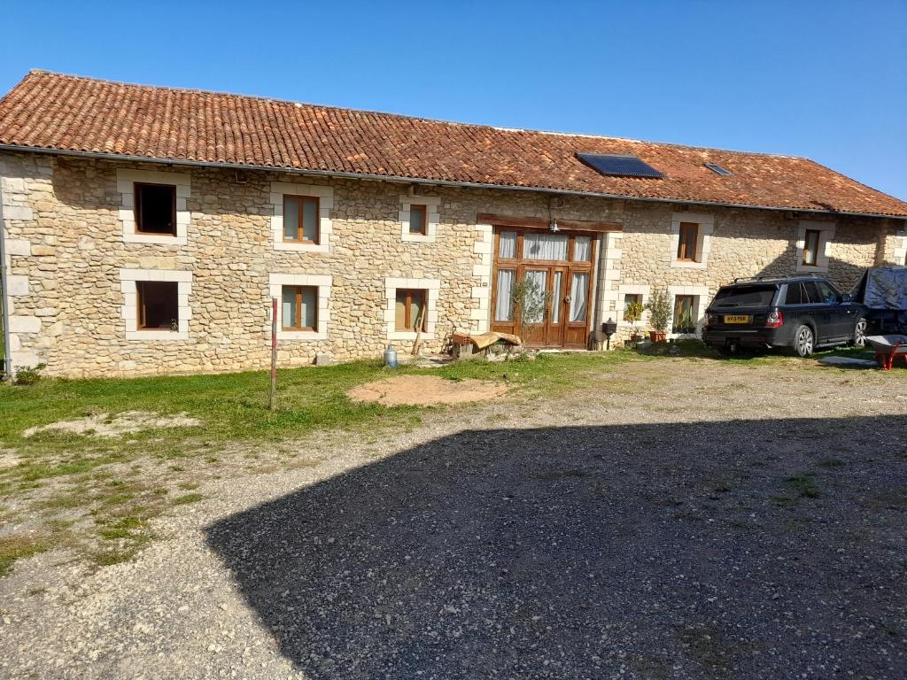 a stone house with a car parked in front of it at A Barn with a View and Tranquility in Varaignes